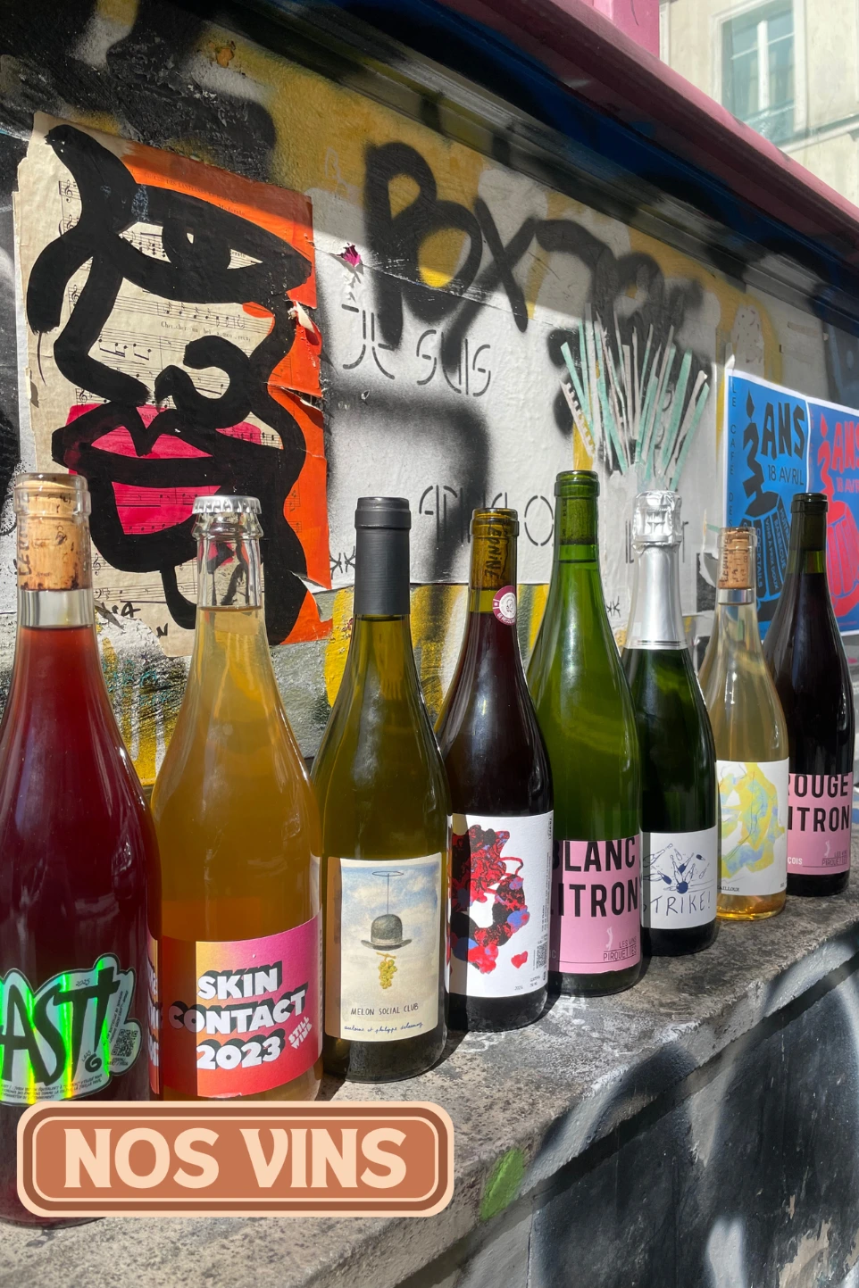 Vins nature du Café des Délices : bouteilles alignées devant un mur graffé